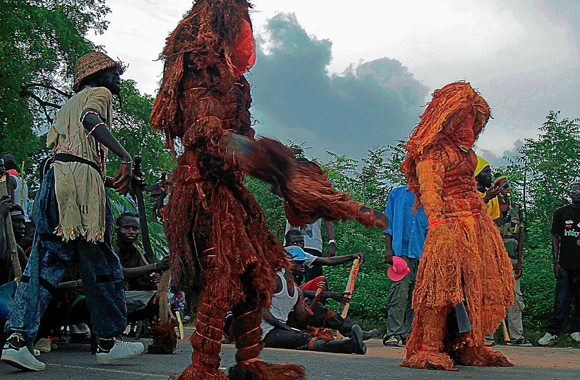 Deux kankourang d'écorce et de fibres dansant au cœur de la foule lors d'un rite diola en Casamance
