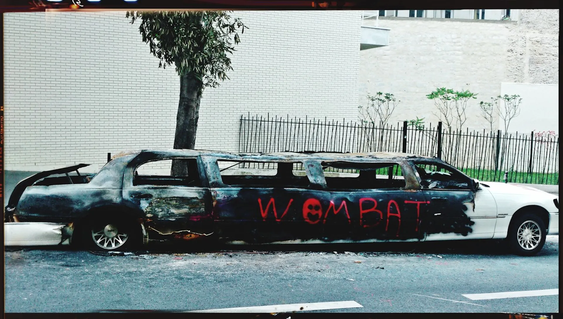 Limousine calcinée et taguée dans une rue de béton — le luxe consumé du monde urbain