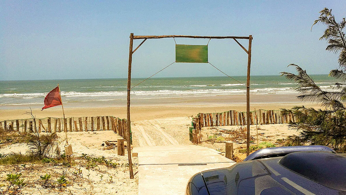 Portail de bois ouvrant sur la plage et l'océan Atlantique devant le Papayer Écolodge
