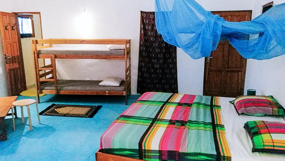 Chambre lumineuse avec moustiquaire, lit double et lits superposés