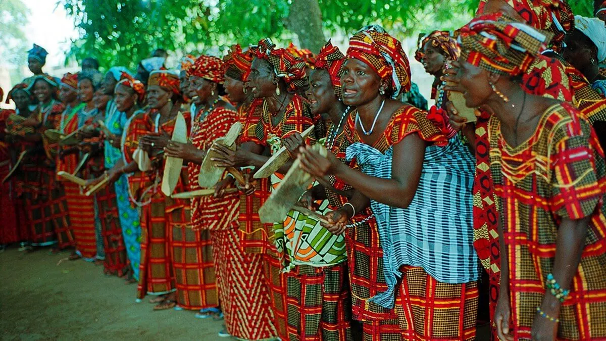 Femmes diolas en tenues colorées chantant et dansant lors d'une soirée culturelle