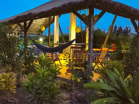Terrasse de l'écolodge au crépuscule avec hamac et lanternes allumées
