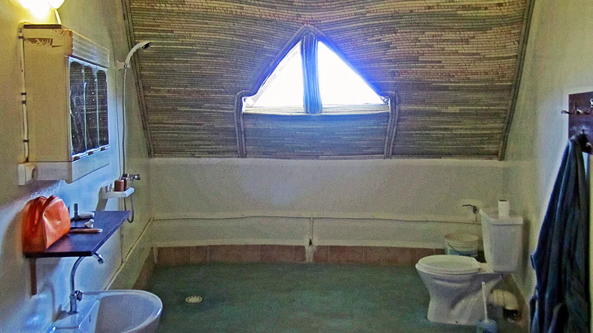 Salle de bains sous un plafond en matériaux tressés avec une fenêtre triangulaire