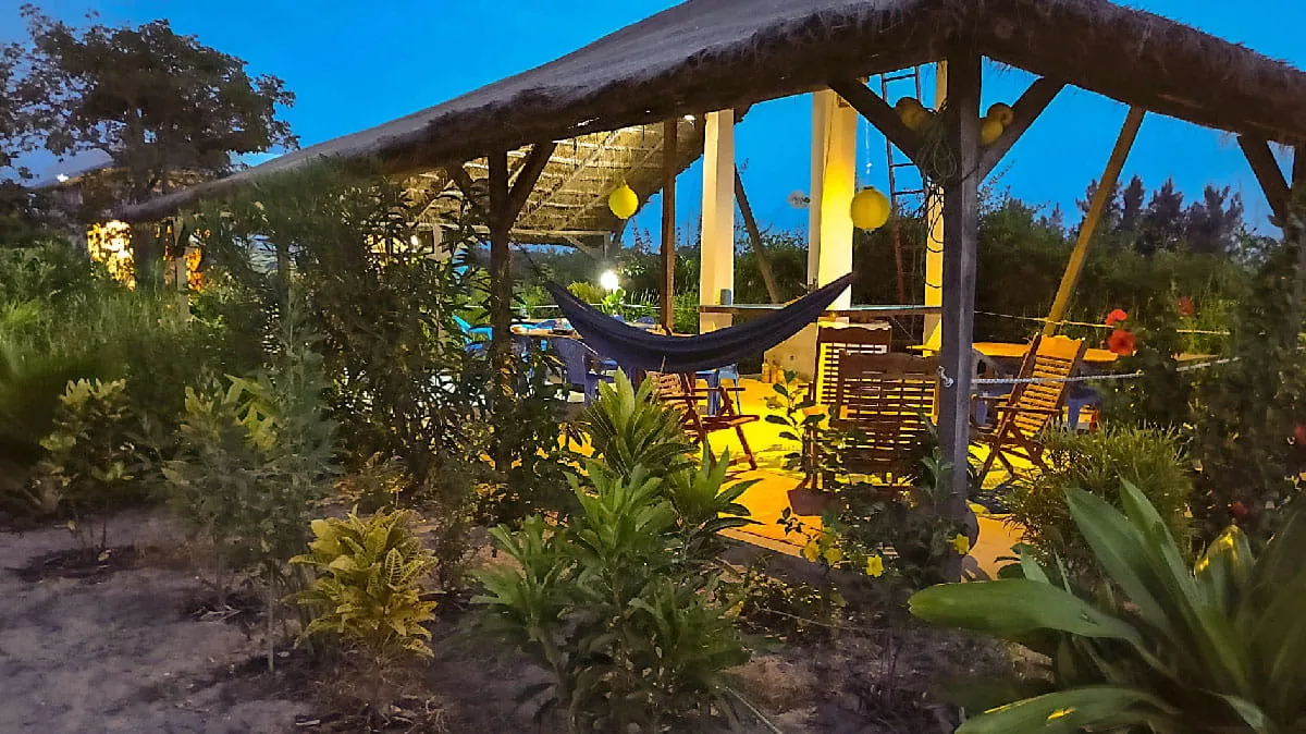 Terrasse de l'écolodge au crépuscule avec hamac et lanternes allumées